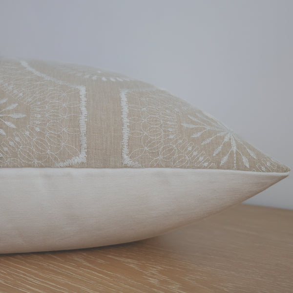 Beige pillow with subtle pattern on a wooden surface