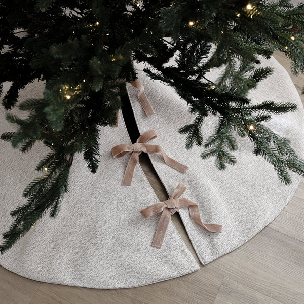 Handmade white velveteen Christmas tree skirt with subtle texture and double-sided velvet ribbon ties beneath an evergreen Christmas tree