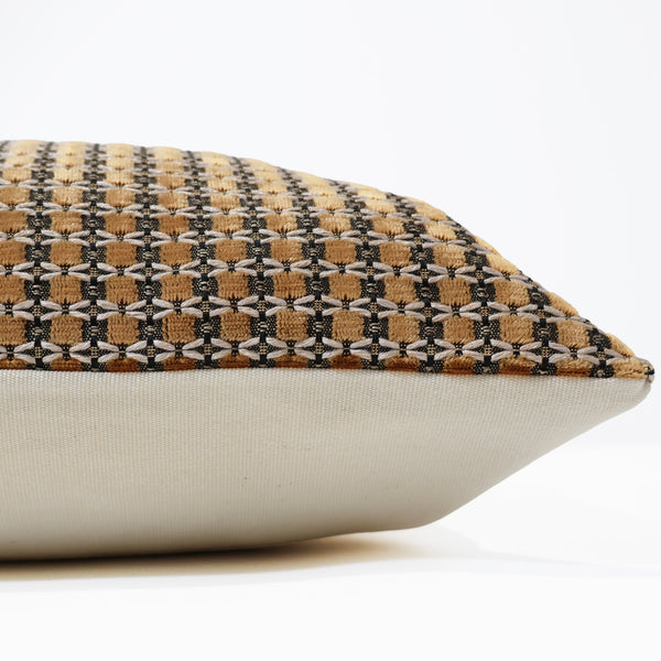 A close-up of a decorative throw pillow showing its patterned top fabric and solid off-white underside on a clean white background.