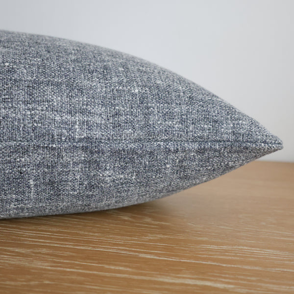 Textured gray pillow on a wooden surface with a neutral background