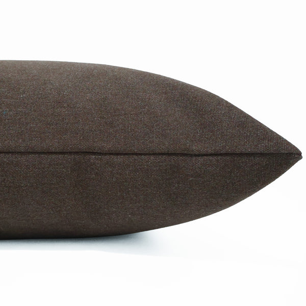A close-up of a dark brown textured throw pillow, showing the fabric weave and stitched seam, on a plain white background.