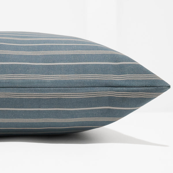 A close-up of a square throw pillow with a blue-gray and beige striped fabric, shown against a clean white background.