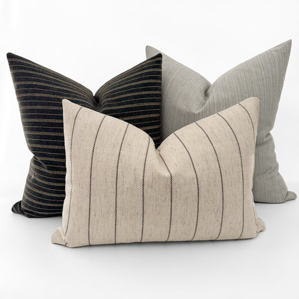 Designer decorative pillow arrangement featuring Hackner Home pillow covers including Jute Stripe in blue-black performance fabric, Antique Stripe Brown, and Subtle Stripe Gray pillow, styled for modern, coastal, organic modern, and transitional home décor.