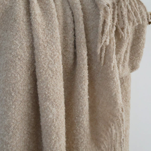 Beige Alpaca Wool textured blanket with tassels draped over a wooden rod against a white background