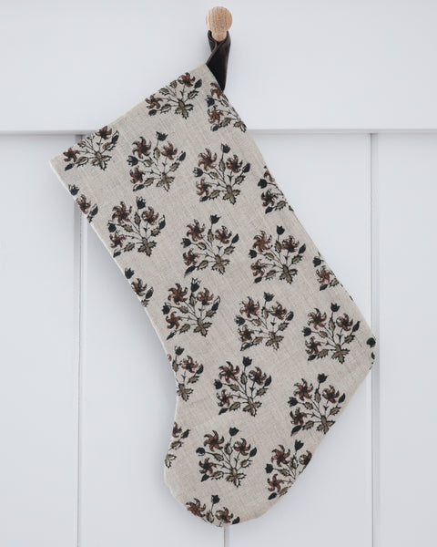 Large linen block print Christmas stocking in a floral pattern with a brown velvet hook loop, shown on a white background