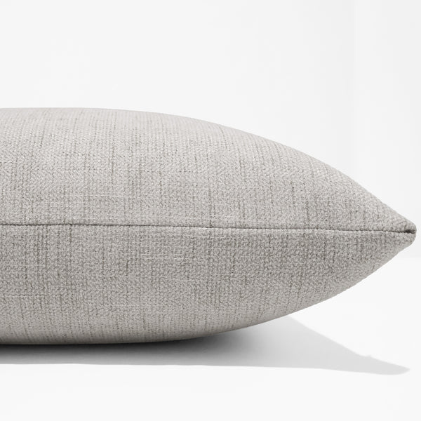 Reeve Woven Oatmeal Pillow Cover styled with linen and striped pillows for a layered look.