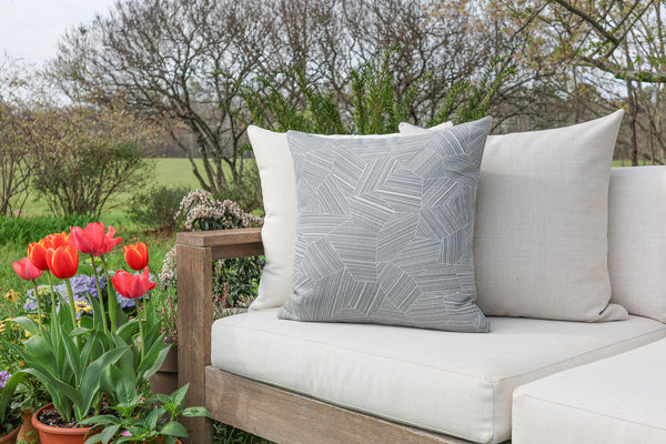 Outdoor setting with a wooden bench featuring patterned cushions and tulips in the foreground.