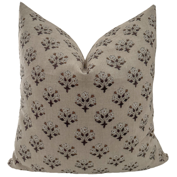 A square-shaped pillow cover with a brown block print floral design on a light linen-colored background.