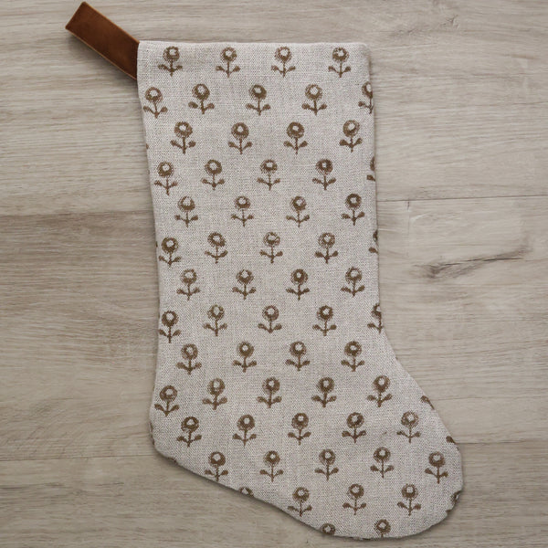 Neutral linen Christmas stocking with a tan floral block print pattern and a brown velvet hanging loop, displayed on a white background.