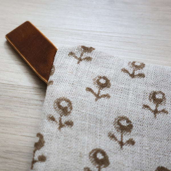 Neutral linen Christmas stocking with a tan floral block print pattern and a brown velvet hanging loop, displayed on a white background.