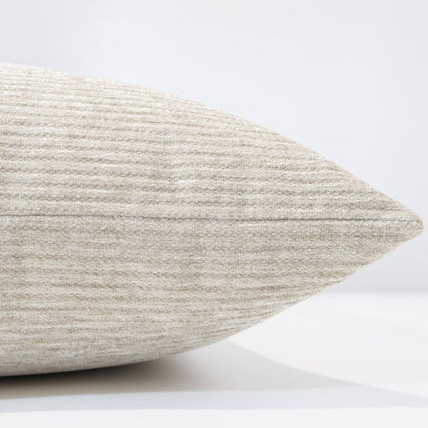 Side view of a beige velvet pillow showcasing its soft ribbed texture, smooth stitching, and light reflective sheen.