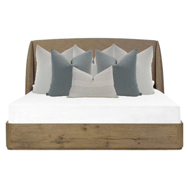 Hackner Home Moonlit Fog bed pillow combo featuring layered blue-gray and ivory decorative pillows on a rustic wood upholstered bed frame.