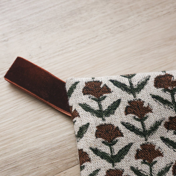 Hackner Home Holly Block Print Boho Christmas Stocking featuring a hand-printed brown and green floral pattern on natural linen with a brown velvet hanging loop.