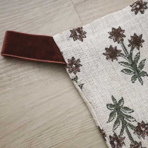 Hackner Home Wood Lily Block Print Large Minimal Christmas Stocking featuring a hand-printed floral pattern in earthy green and brown tones on a natural linen background with a velvet hanging loop.